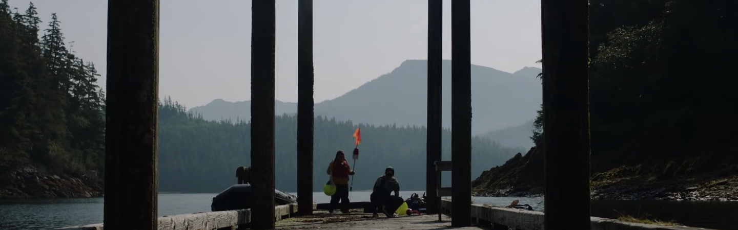 Two people on dock holding red flags.