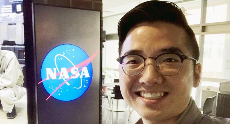 Eunsang standing next to NASA logo sign inside building.