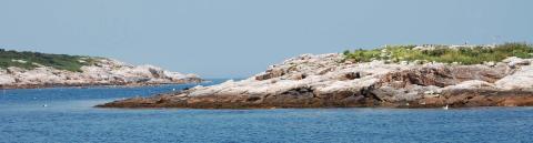 Two rocky islands are separated by a small segment of ocean. 