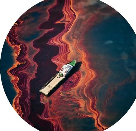 A ship drifts amidst a heavy band of oil spilled in the Gulf of Mexico from the Deepwater Horizon wellhead, May, 2010, by Daniel Beltrá