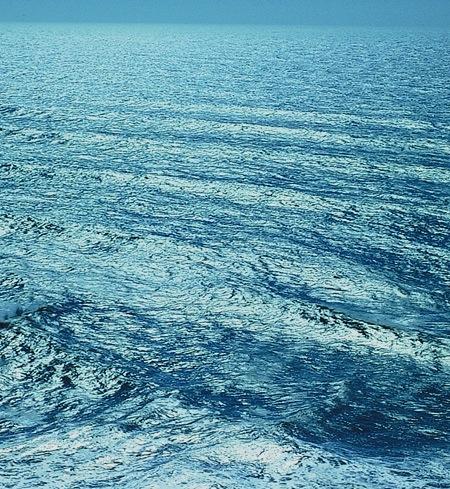 Photo of blue waves in succession on ocean surface.