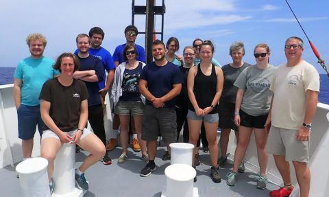 Photo of smiling group of people on a boat at sea. 