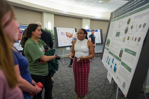 Photo of student giving poster presentation. 