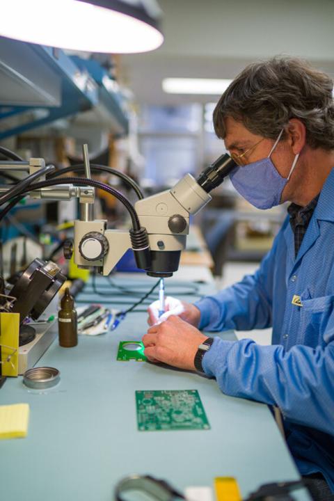Photo of a researcher looking through a microscope in a lab. 