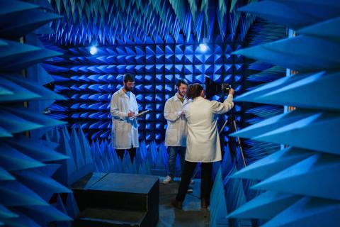 Photo of 3 researchers in lab coats inside blue spike chamber. 