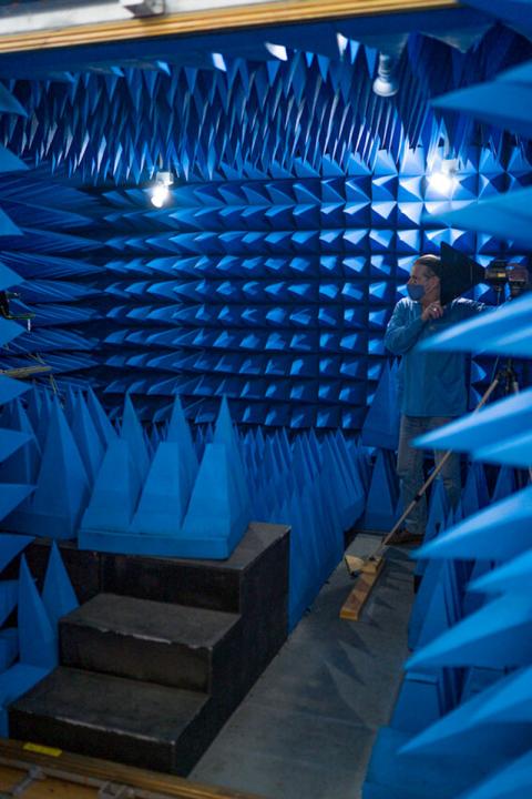 Researcher in chamber surrounded by blue spikes on walls. 
