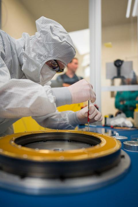 Researcher using a screwdriver in lab on circular instrument. 