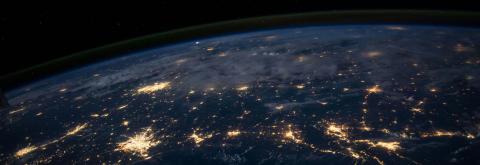 Photo of Earth from space with glowing lights on land. 