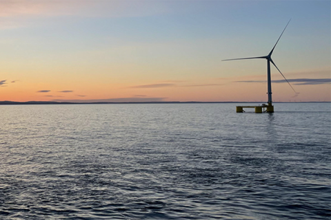 Image of a wind turbine in the ocean at sunset.