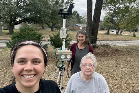 Three researchers installing air pollution sensors in a backyard in Pascagoula, MS.