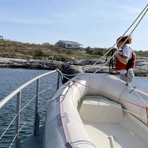 Photo of woman on front of boat holding ropes.
