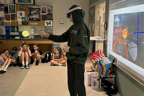 Student playing with VR goggles on in classroom. 
