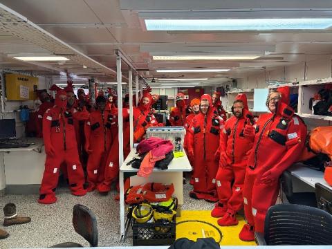 AR103 participants in survival suits as part of vessel safety briefing