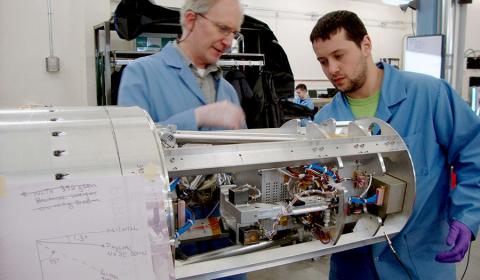 Photo of two men integrating and testing the ERPA instrument for the MICA rocket mission.