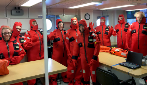 Hilary (fourth from left) and colleagues learn how to put on and take off immersion suits in case there are emergencies that require jumping ship. Group of students in their red immersion suits.