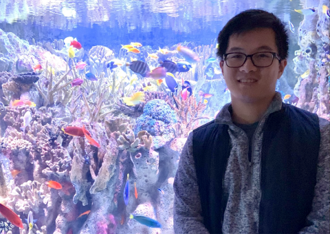 Photo of James standing in front of a colorful fishtank.