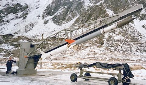 Thom Moore with the Poleward Leap rocket payload at Andenes, Norway c 1981. Man standing against a rocket on a launcher.