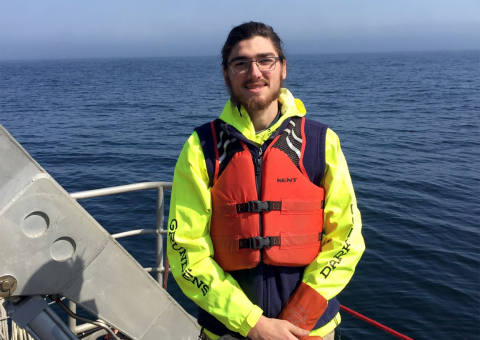 Photo of Terrence standing on a boat with a life jacket.